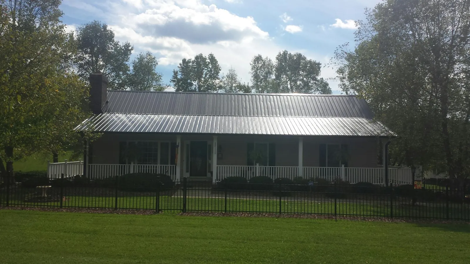 Gray metal roof on a brick ranch with a full width front porch — Gutter Guard Installation work by our crew in Gallitzin