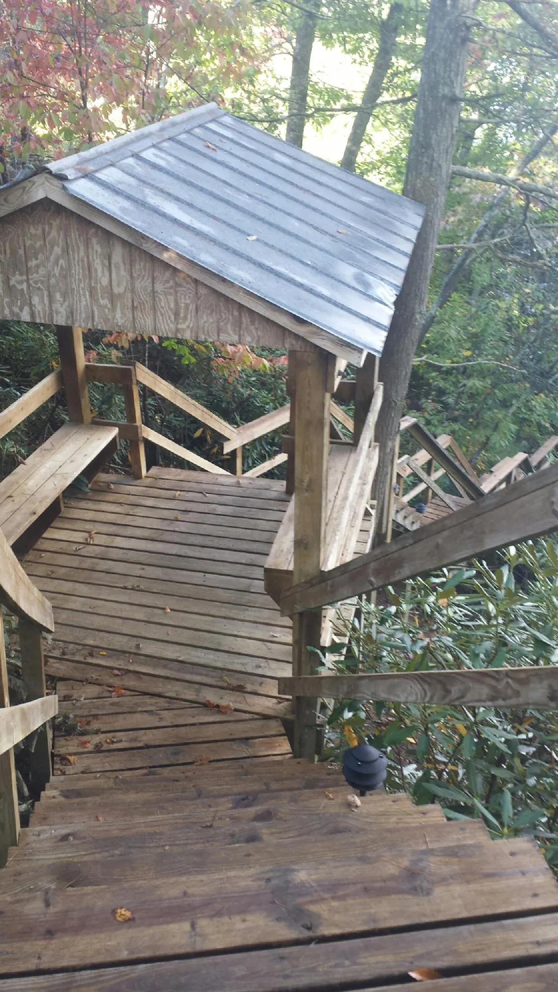 Metal roofed shelter over wooden steps on a wooded walkway — Skylight Repair & Installation work by our crew in Gallitzin